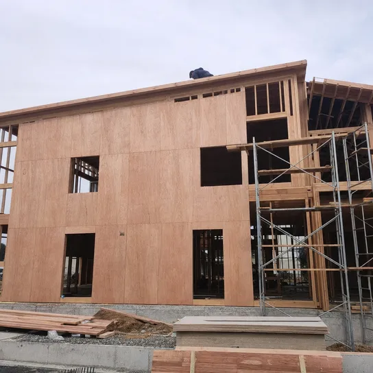 Exterior plywood wall sheathing on timber frame building under construction