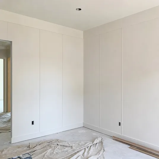 Primed hardboard sheets installed as interior wall panelling ready for painting